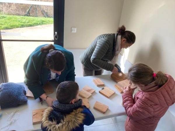 Deux adultes et deux enfants font du bricolage avec des planches en bois