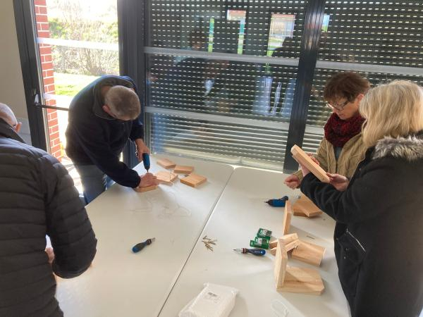 Quatre adultes font du bricolage avec des planches en bois