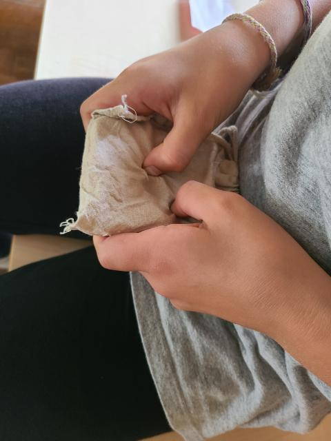 Gros plan sur des mains d'enfant tenant un pochon pour deviner au toucher l'espèce animale qui a laissé l'empreinte à l'intérieur